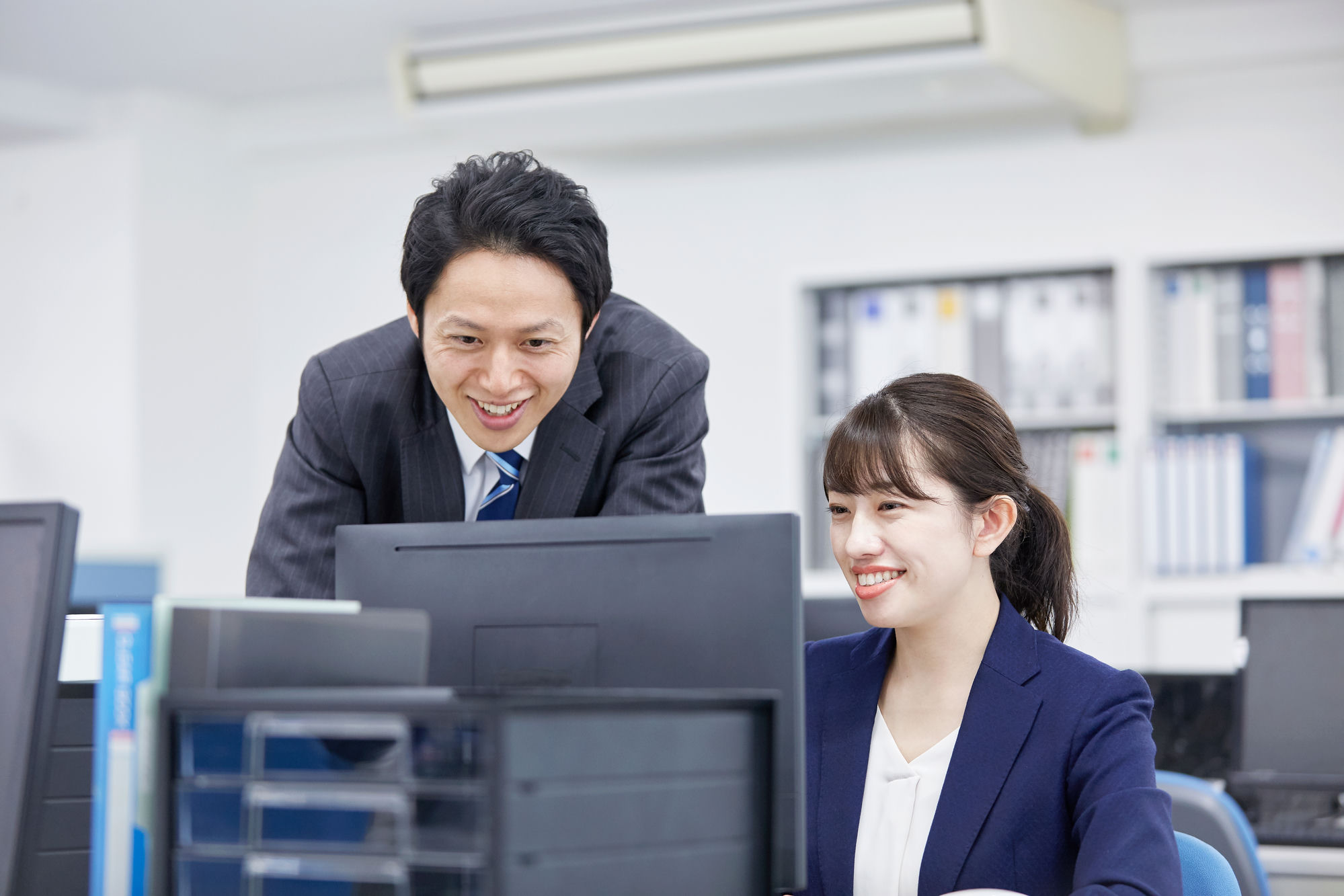 オフィスでスーツの社員がPCでAIを活用する様子